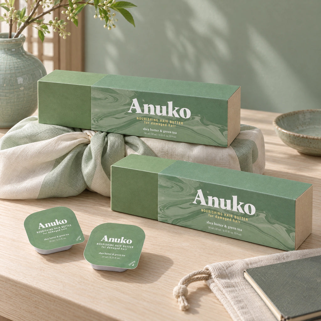 Two Travel Hair Butter cases, one on a knotted bojagi gift wrap, with capsules, a linen pouch and a notebook